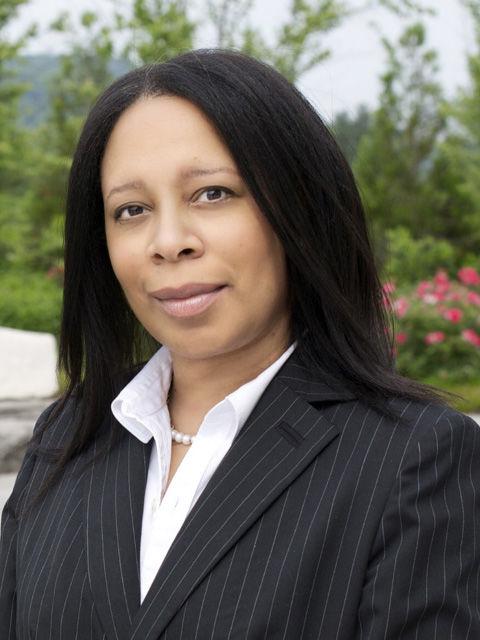 woman looking at camera with a slight smile, in dark suit jacket and white blouse.